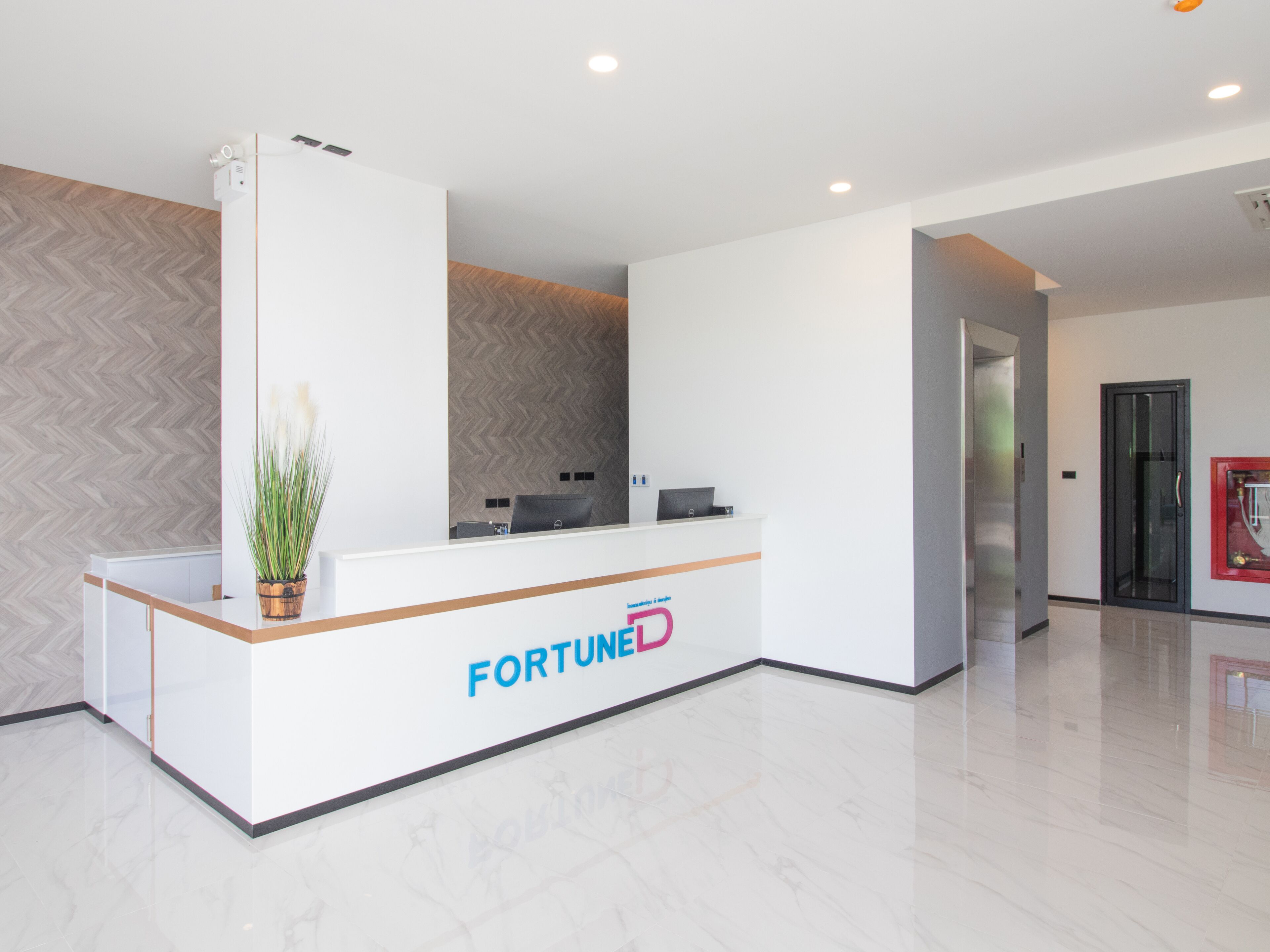 Un mostrador de recepción con el logotipo 'FORTUNE', una planta en maceta y un diseño de interiores moderno.