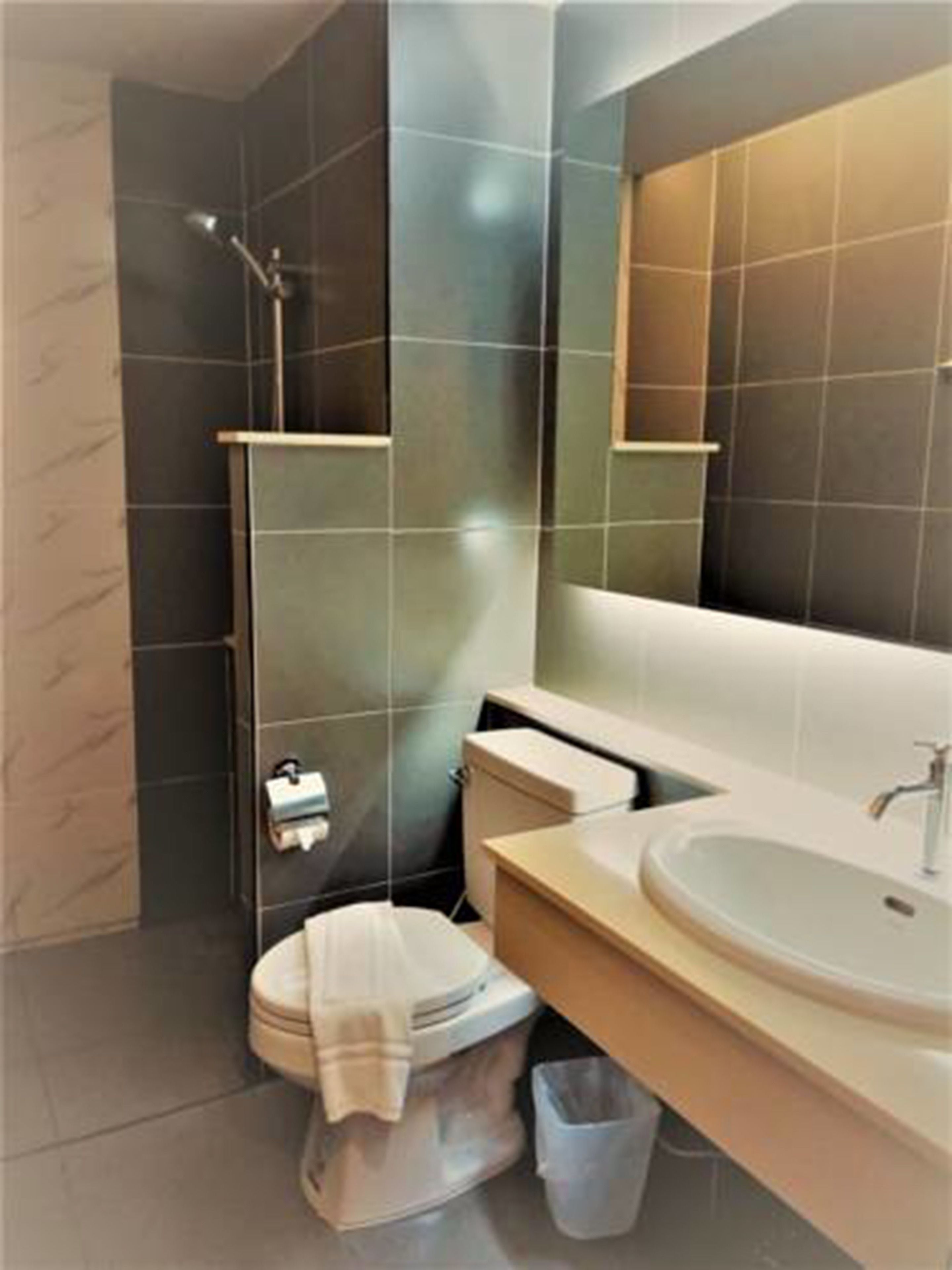 Un baño moderno con cabina de ducha de vidrio, inodoro y lavamanos con espejo.