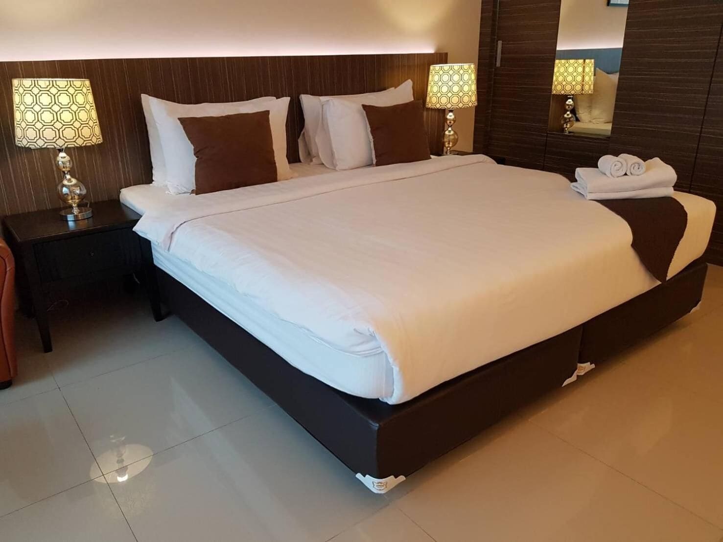 A large bed with white linens, two nightstands with lamps, and a mirror on the wall.