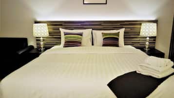 A neatly made bed with striped pillows, a headboard with horizontal wooden slats, two bedside lamps with patterned lampshades, and a framed picture on the wall.