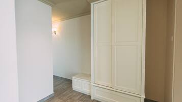 Una habitación con un armario blanco grande, un banco y una lámpara fijada a la pared.