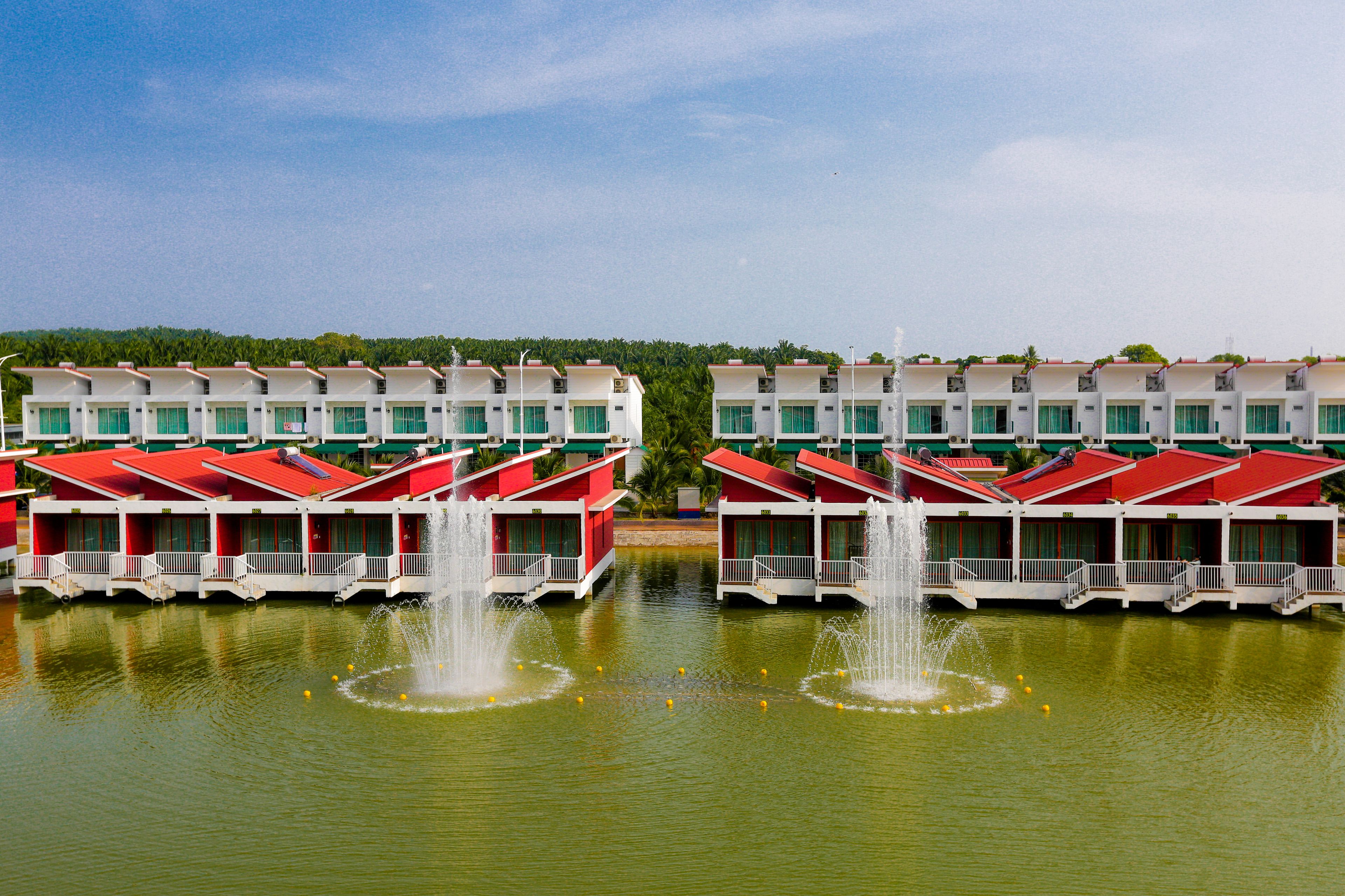 A row of red and white buildings with water fountains in the foreground.