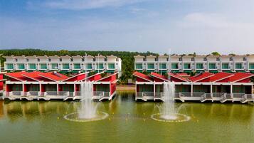 A row of red and white buildings with water fountains in the foreground.