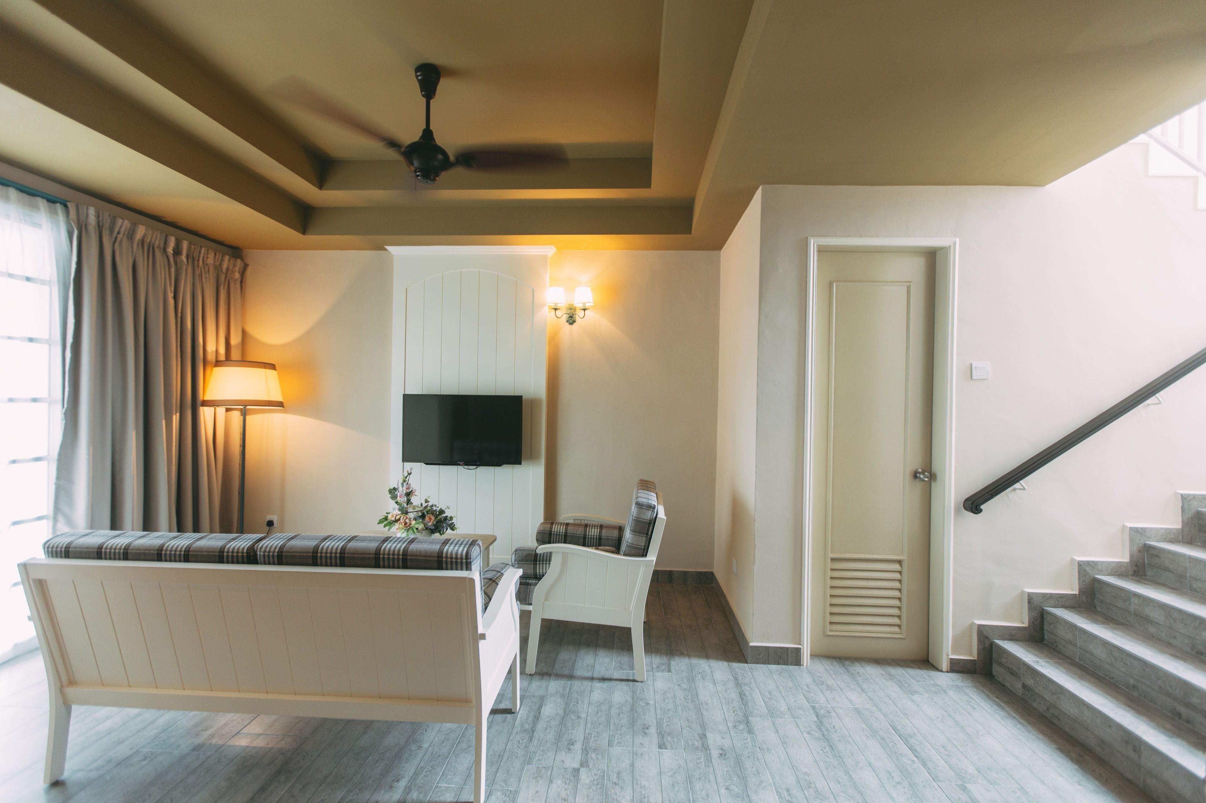 Un salon avec un canapé, un fauteuil, un téléviseur et un escalier.