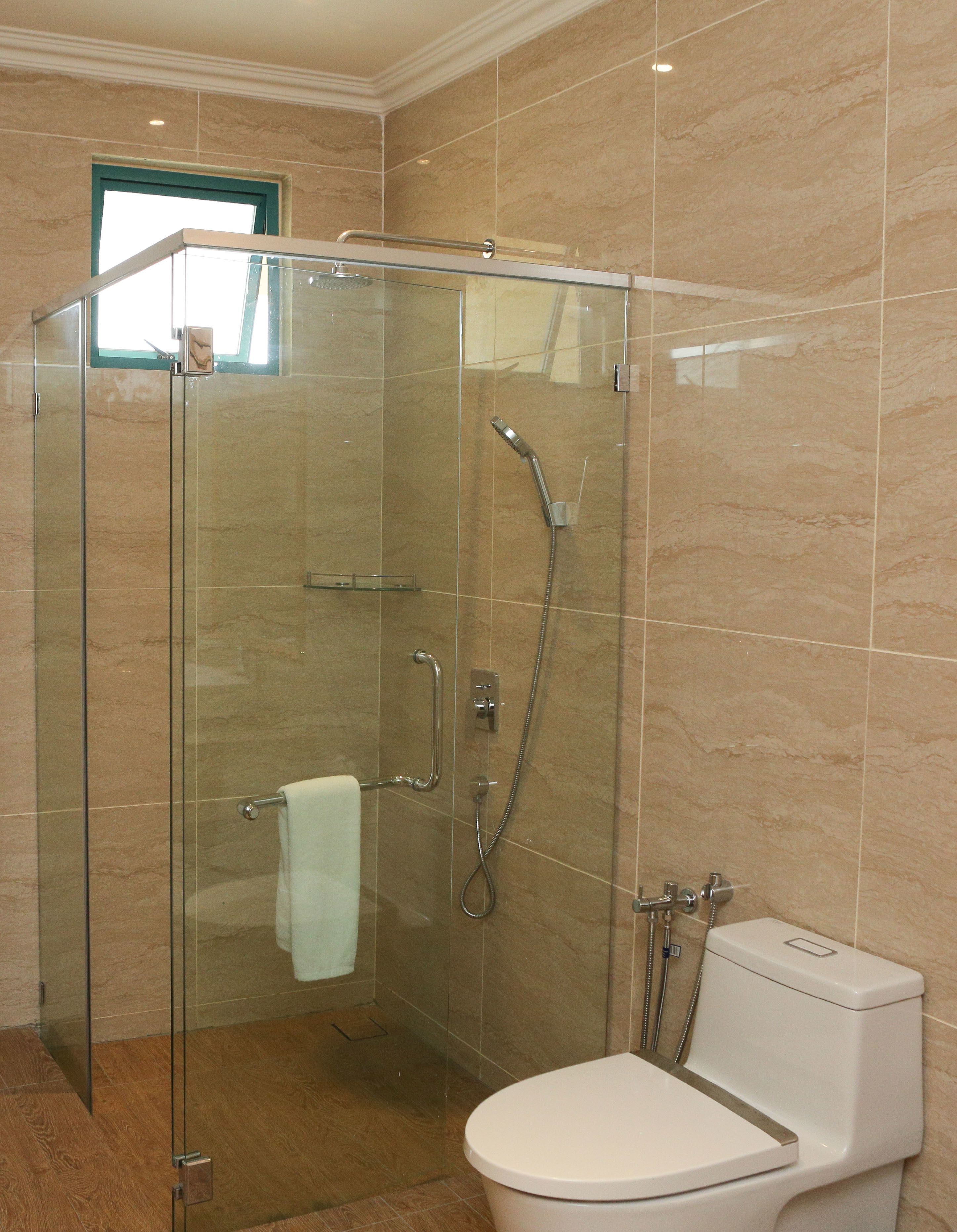 A modern bathroom with a glass-enclosed shower, a toilet, and a glass door.