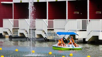 A boat ride with a fountain in the background and a building with balconies.