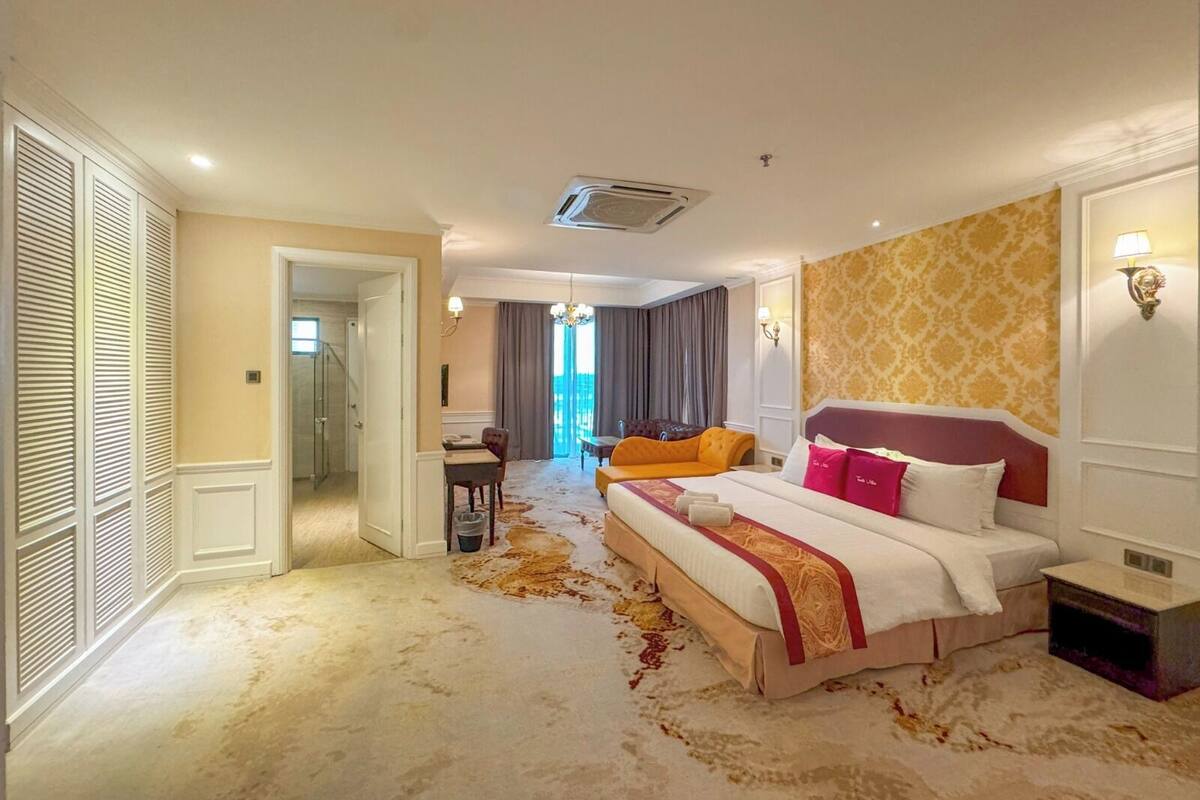 A hotel room with a large bed, a desk, a chair, and a view of the outdoors.