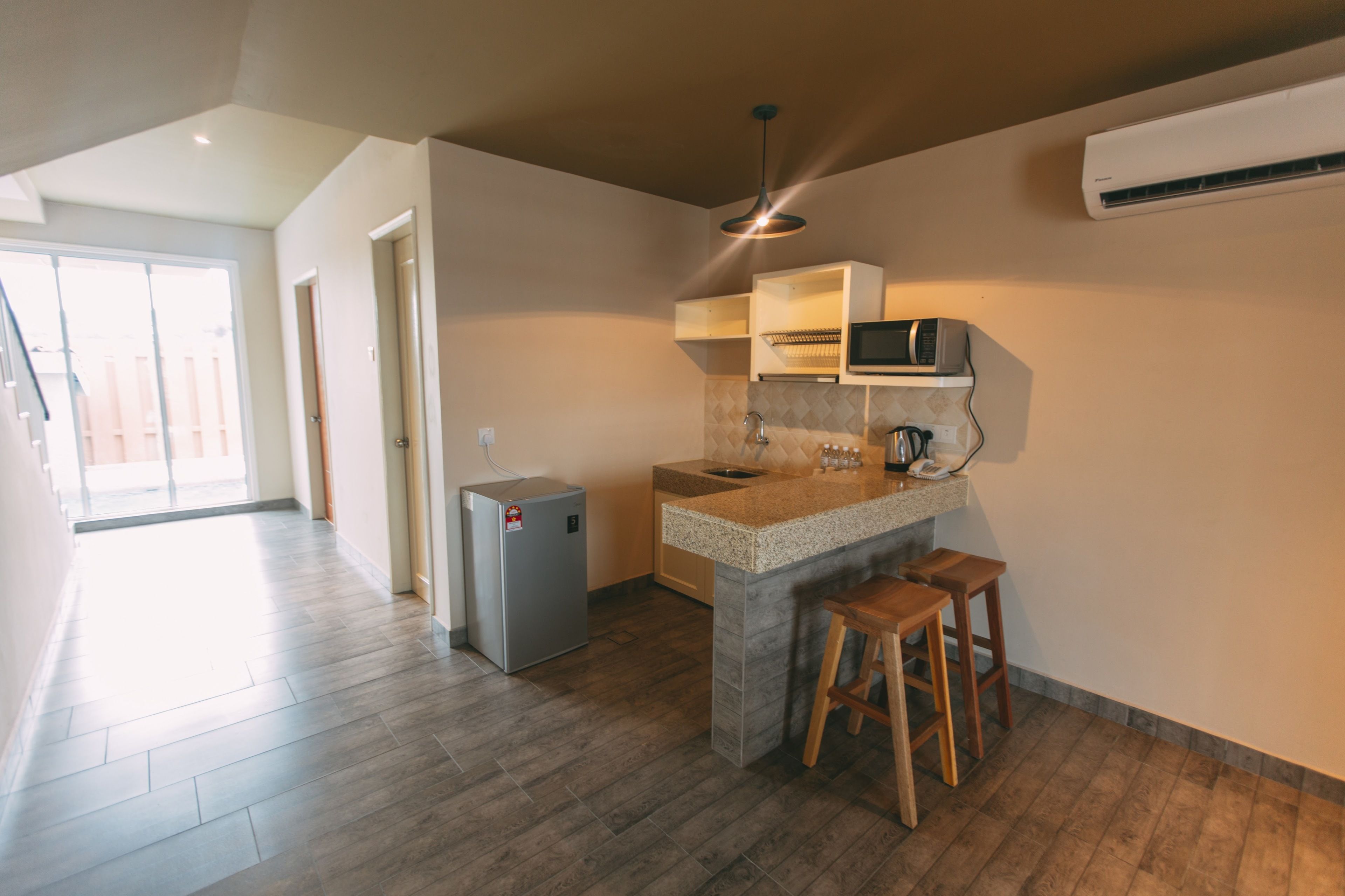 Una cucina moderna con forno a microonde integrato, un piccolo frigorifero e sgabelli in legno.