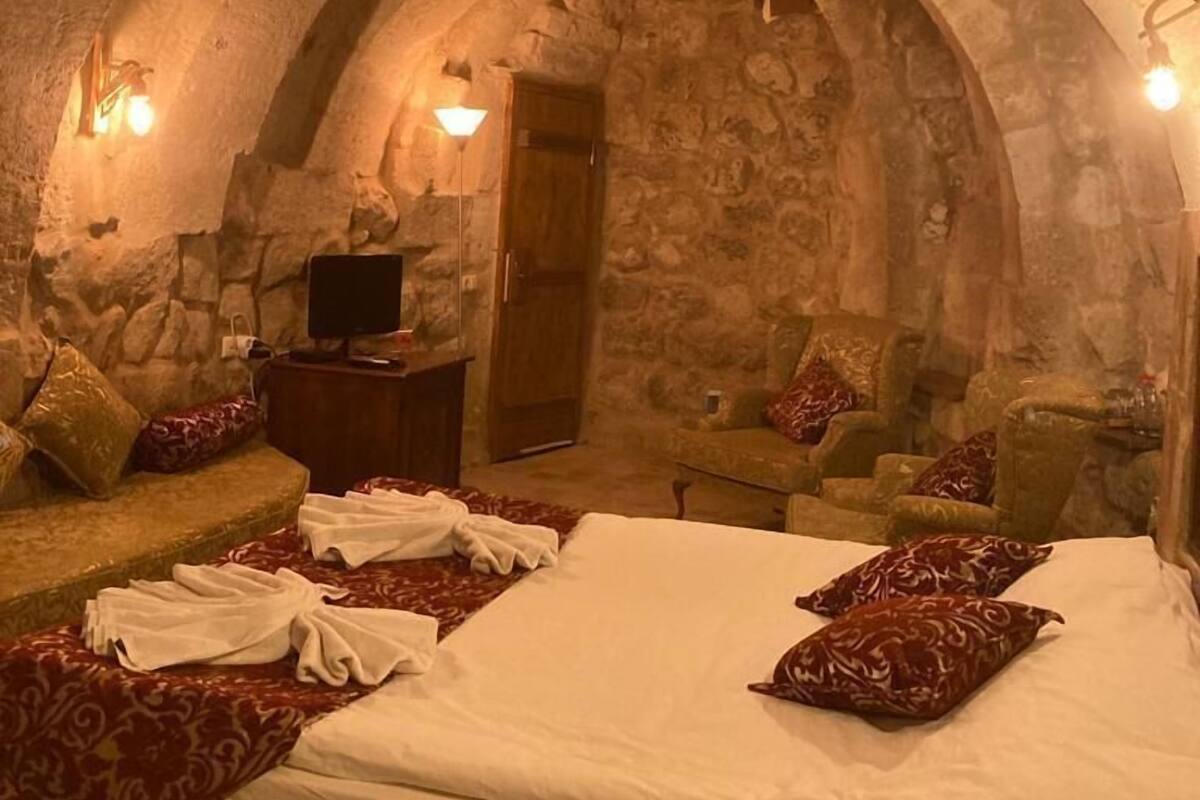 A stone-walled room with a bed, a television, and seating areas.
