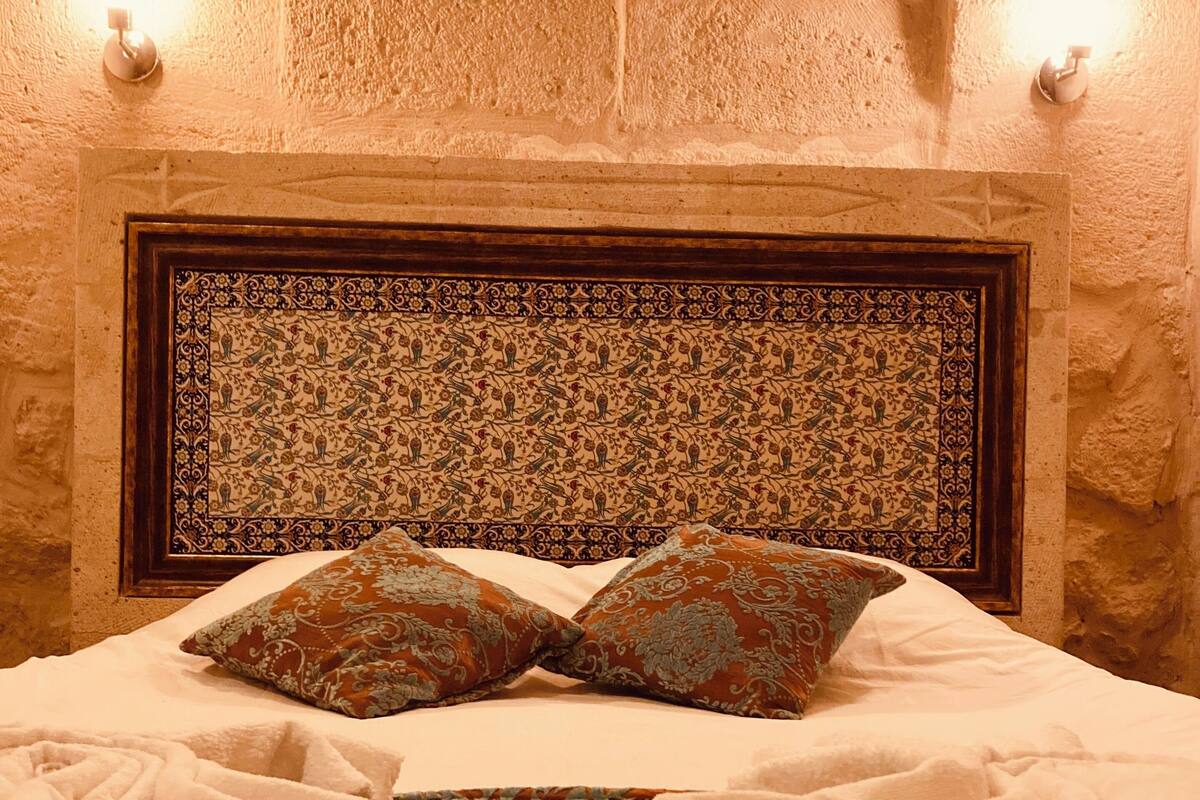 A bed with a patterned headboard, two pillows, and a decorative throw.
