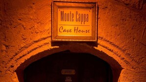 En trädörr med en skylt ovanför som lyder: ”Monte Cappa, grottbostad”.