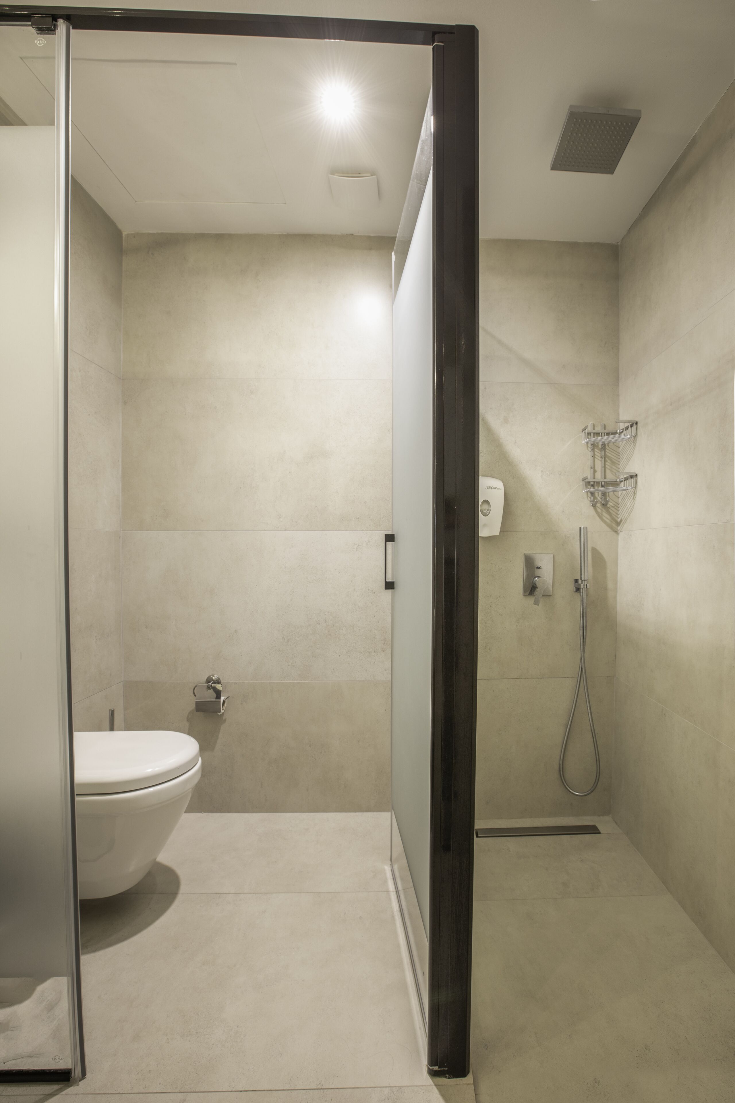 Un baño moderno con inodoro, ducha y cabina de ducha con paredes de vidrio.