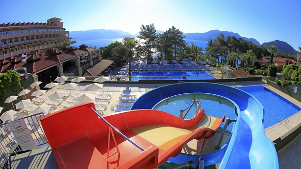 Un parc aquatique doté d’une grande piscine, de toboggans et de chaises longues.