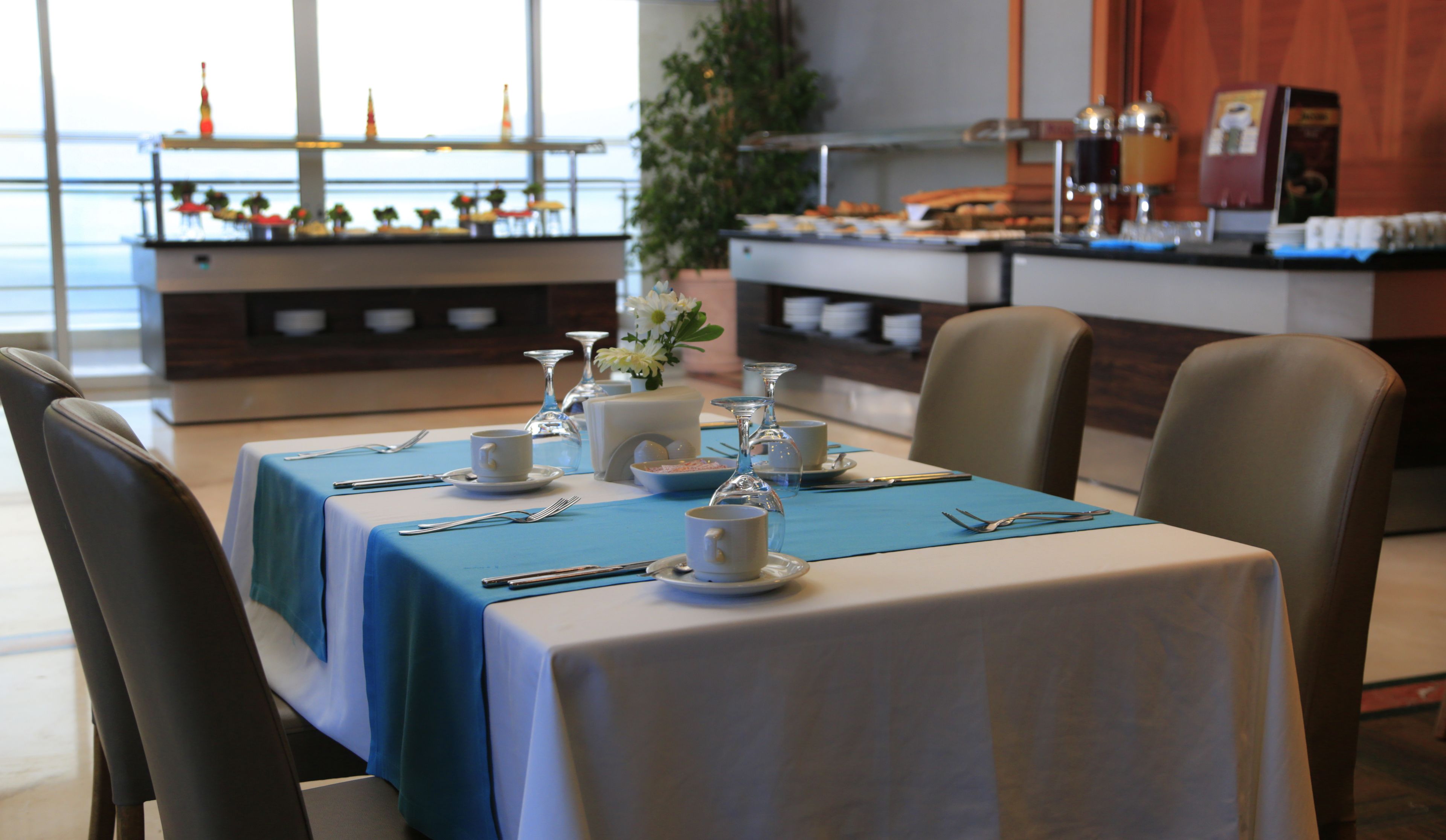 Ein Essbereich mit gedeckten Tischen, Stühlen und einem Buffet im Hintergrund.