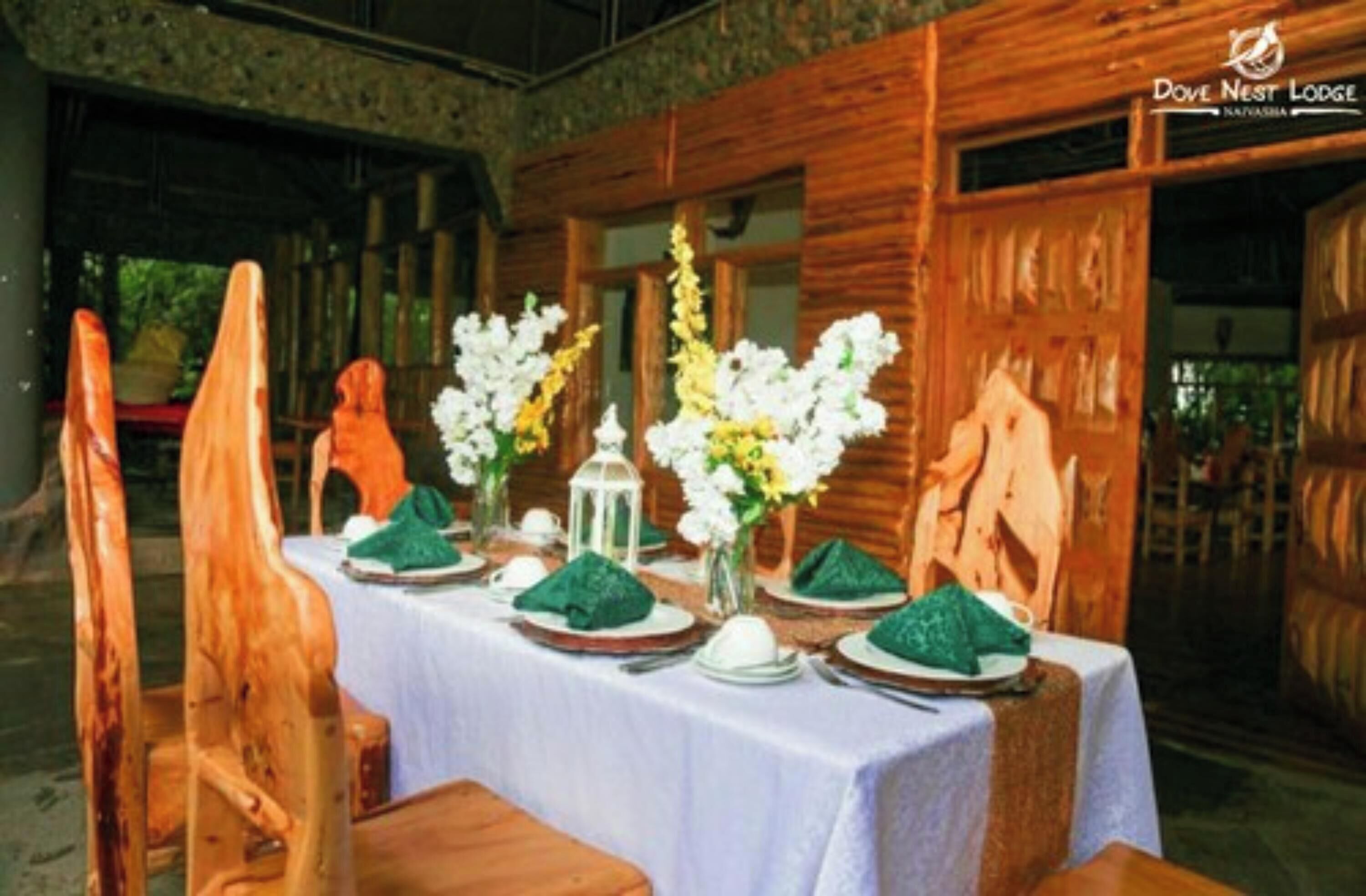 A dining table set with white flowers, green napkins, and a lantern.