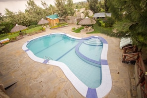 A swimming pool with a stone deck, surrounded by lounge chairs and umbrellas. - Dove Nest Lodge (Naivasha)