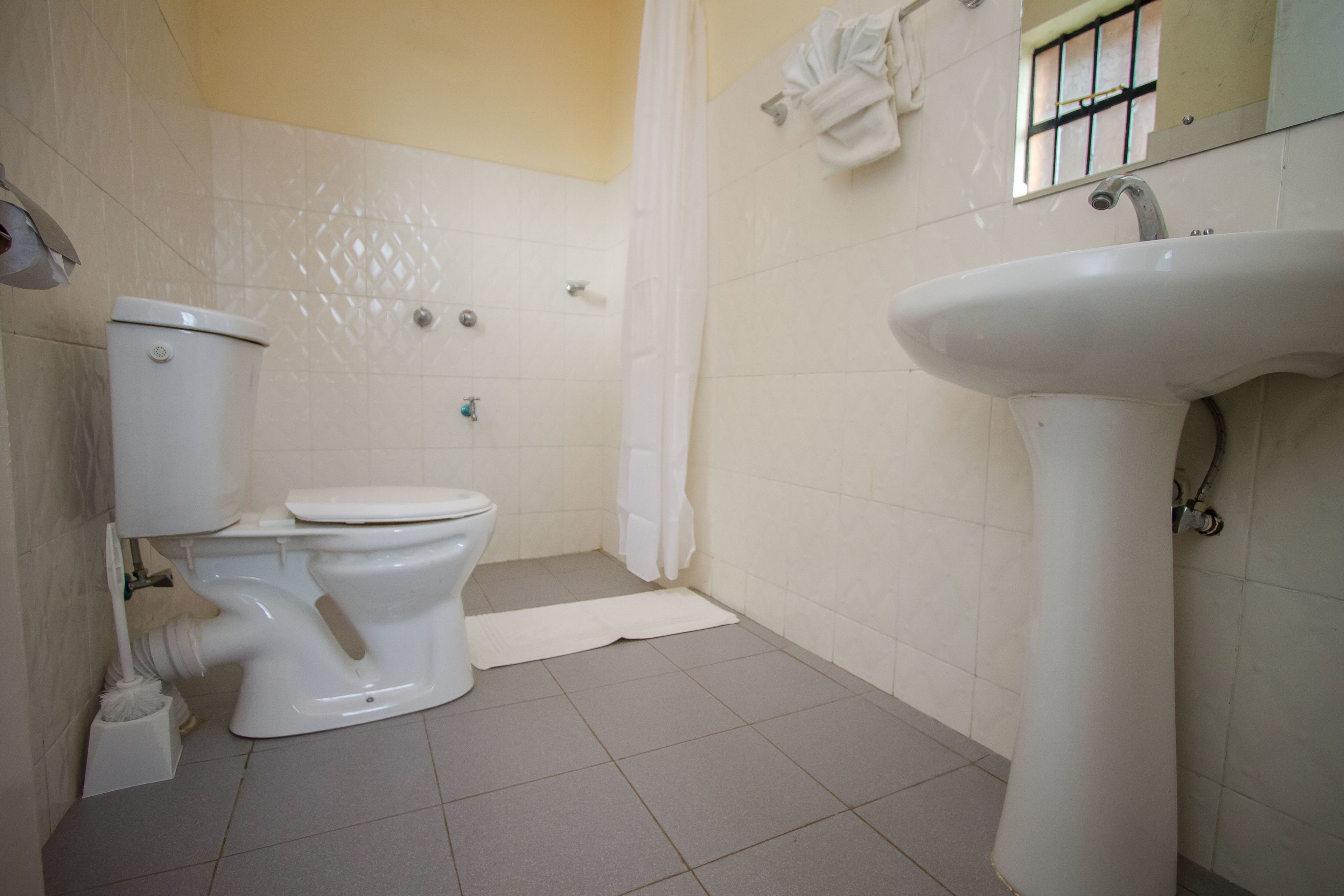 Un baño con inodoro, lavamanos y cortina de ducha.