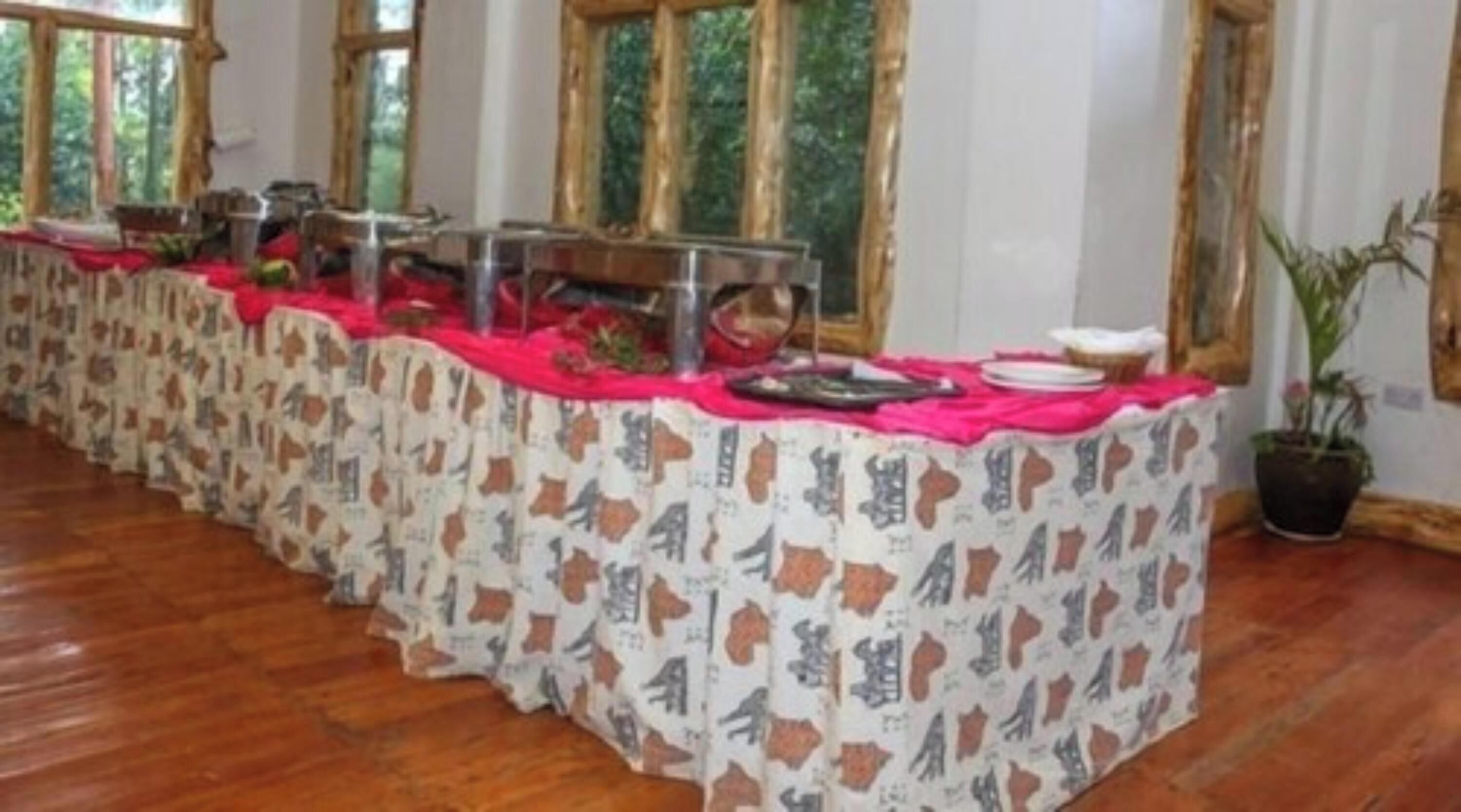 Une longue table recouverte d’une nappe à motifs, sur laquelle sont disposés divers plats et une plante en pot.