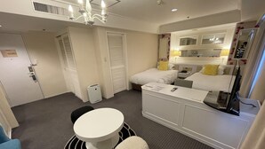 Une chambre d’h ôtel comprenant un lit, une table de chevet, un miroir et une petite table ronde avec une chaise.
