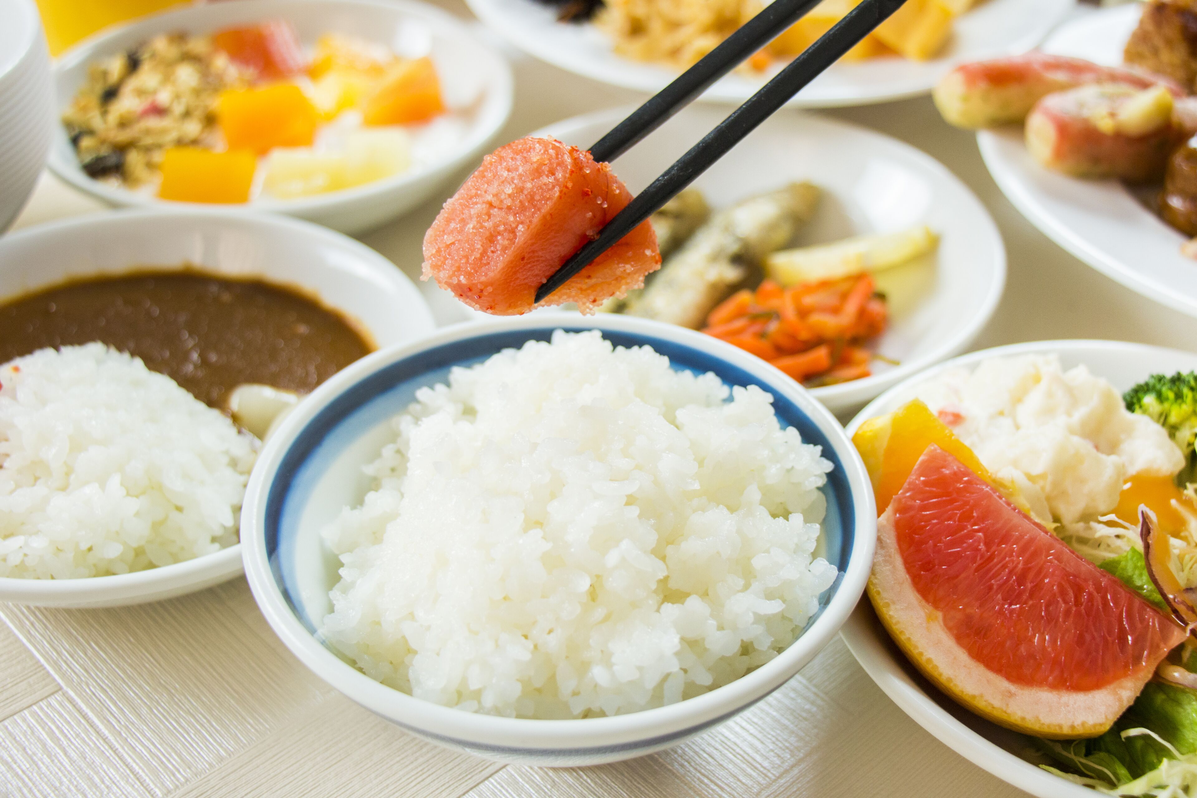A variety of dishes including rice, a citrus fruit, and other foods on a table.