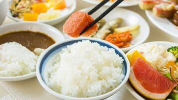 A variety of dishes including rice, a citrus fruit, and other foods on a table.