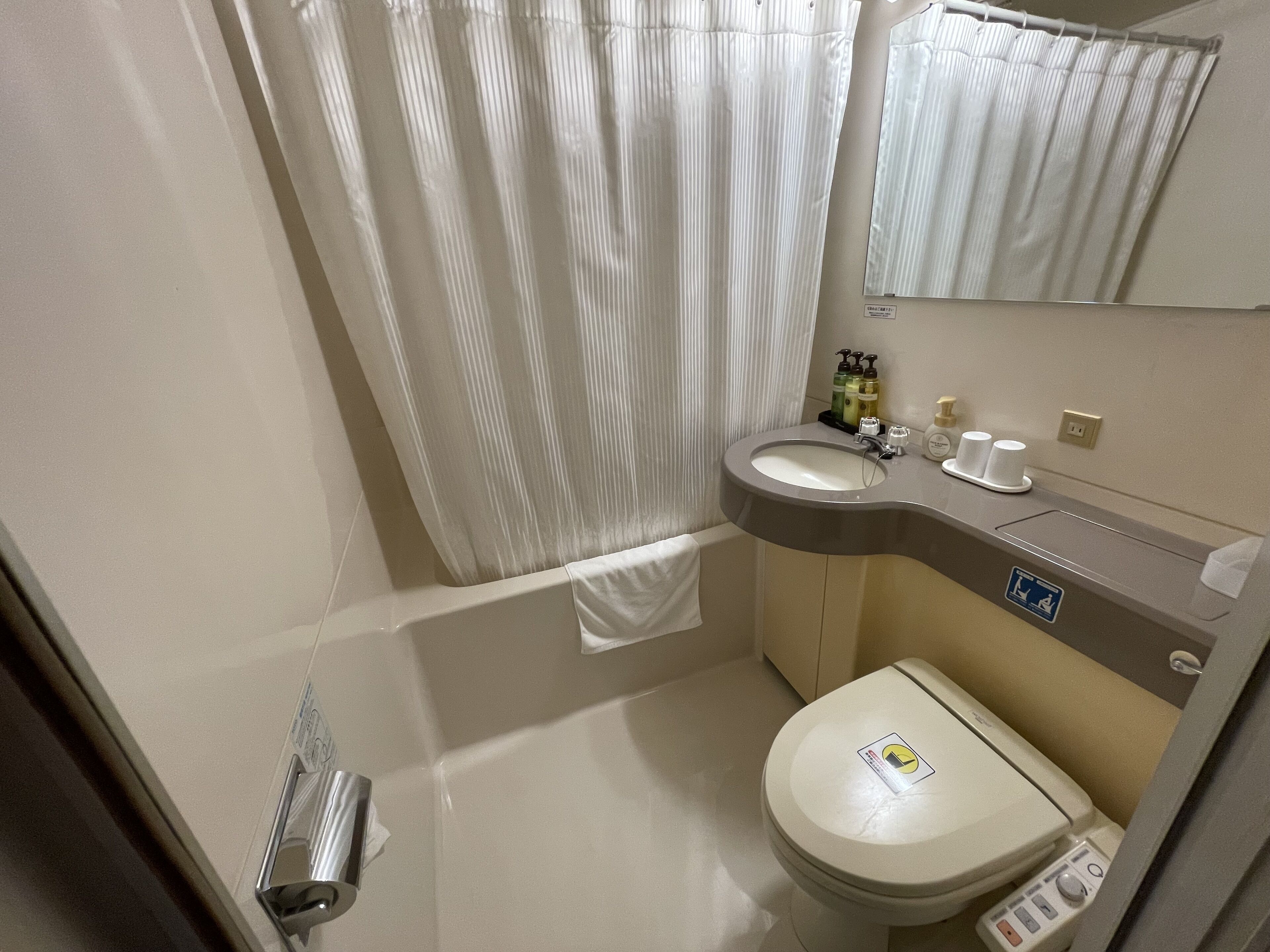 Un baño con inodoro, lavamanos y cortina de ducha.