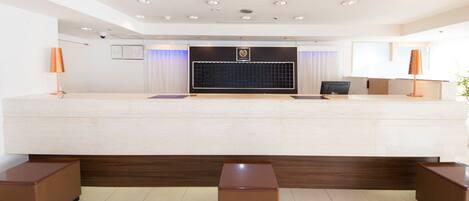 A reception area with a reception desk, a computer, and two lamps.