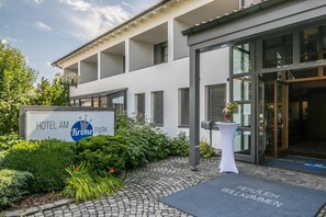 A modern hotel entrance with a sign reading "HOTEL AM Krone PARK". - Hotel am Krone Park (Olching)