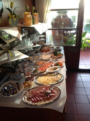 A buffet with various food items, including meats, cheeses, and fruits, arranged on a table. - Hotel am Krone Park (Olching)