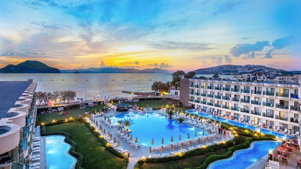 A resort with a large pool surrounded by sun loungers and umbrellas, a beachfront view, and a modern hotel building. - Kairaba Bodrum Princess & SPA (Bodrum)
