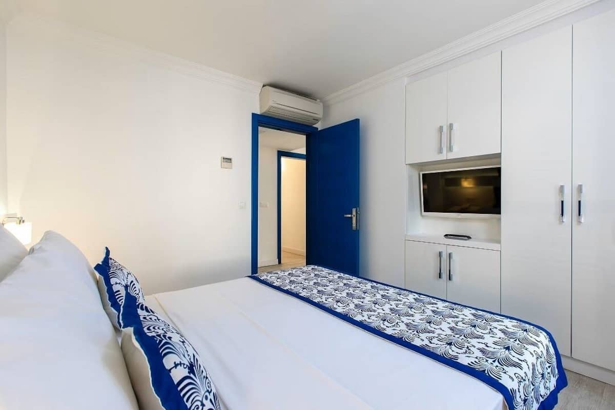 A bedroom with a bed, a TV, and white cabinets.