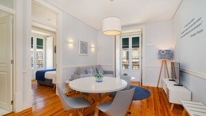Un comedor moderno con una mesa redonda, sillas grises y una lámpara de techo blanca.