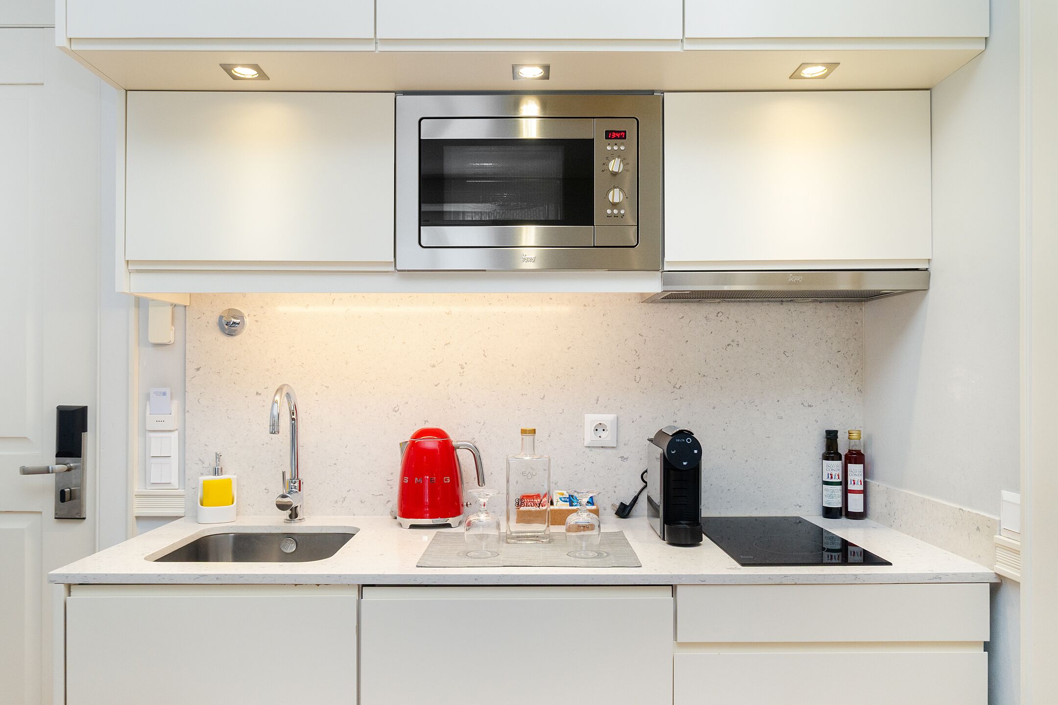 Eine moderne Küche mit Einbau-Mikrowelle, Kaffeemaschine und einer Weinflasche.