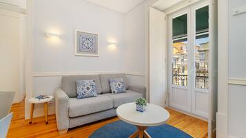Una sala de estar moderna con un sofá gris, una mesita redonda y una alfombra azul.
