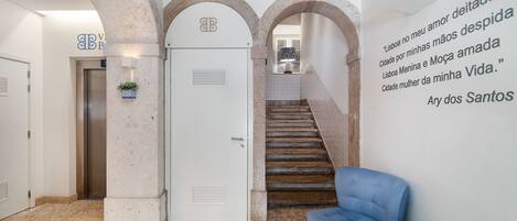 A hotel lobby with a reception desk, a staircase, and a wall with a quote.