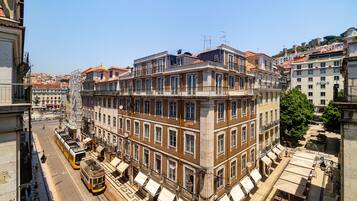 A historic building with multiple floors, large windows, and a tram line running in front.