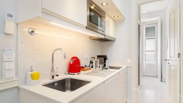 A modern kitchen with a double sink, stainless steel appliances, and a red kettle.