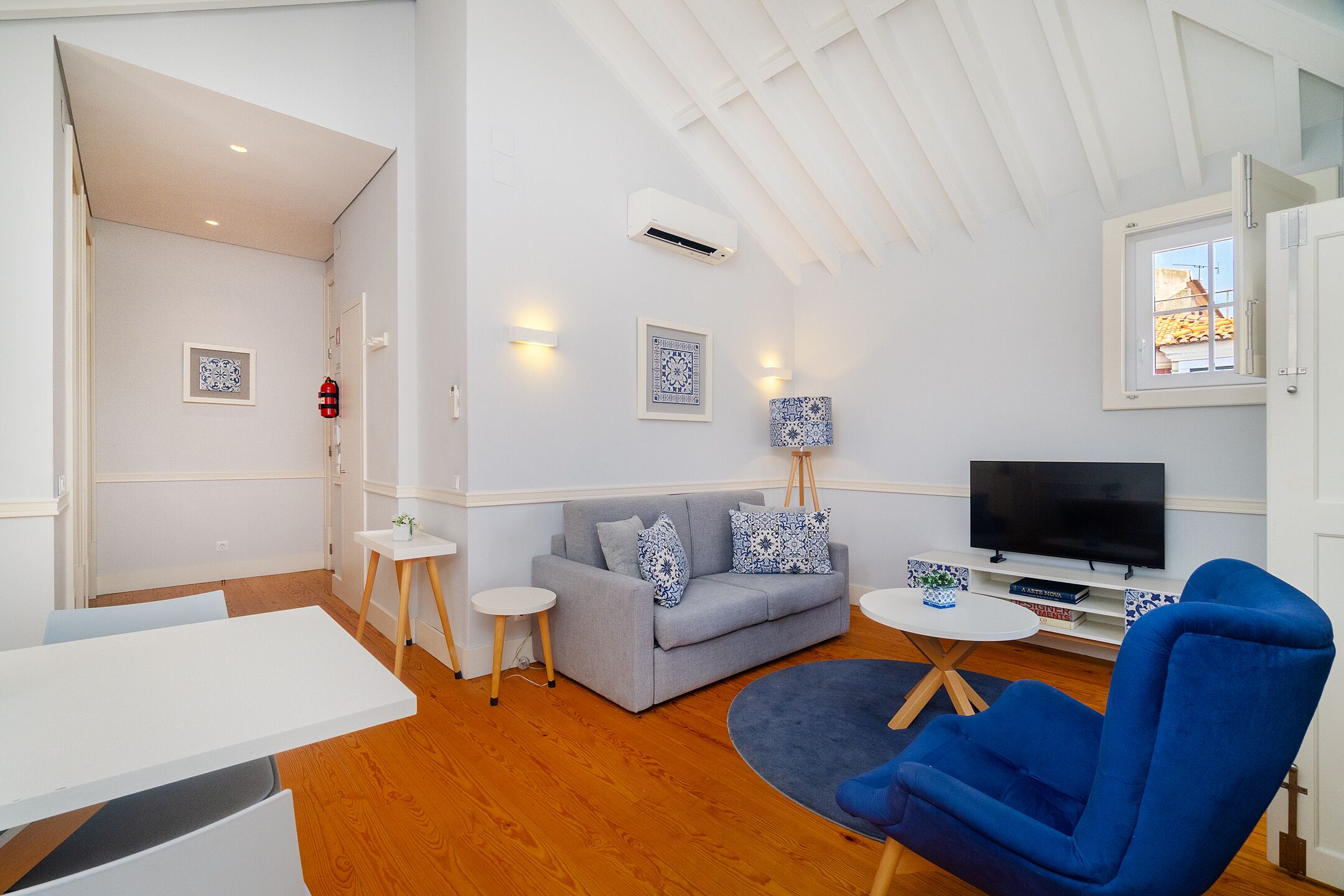 A modern living room with a grey sofa, blue armchair, and a flat-screen TV.