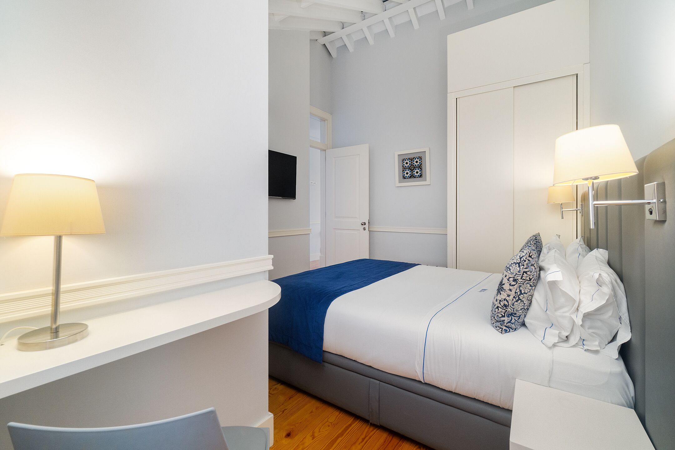 Une chambre à coucher avec un lit, des lampes de chevet, une télévision et une porte.