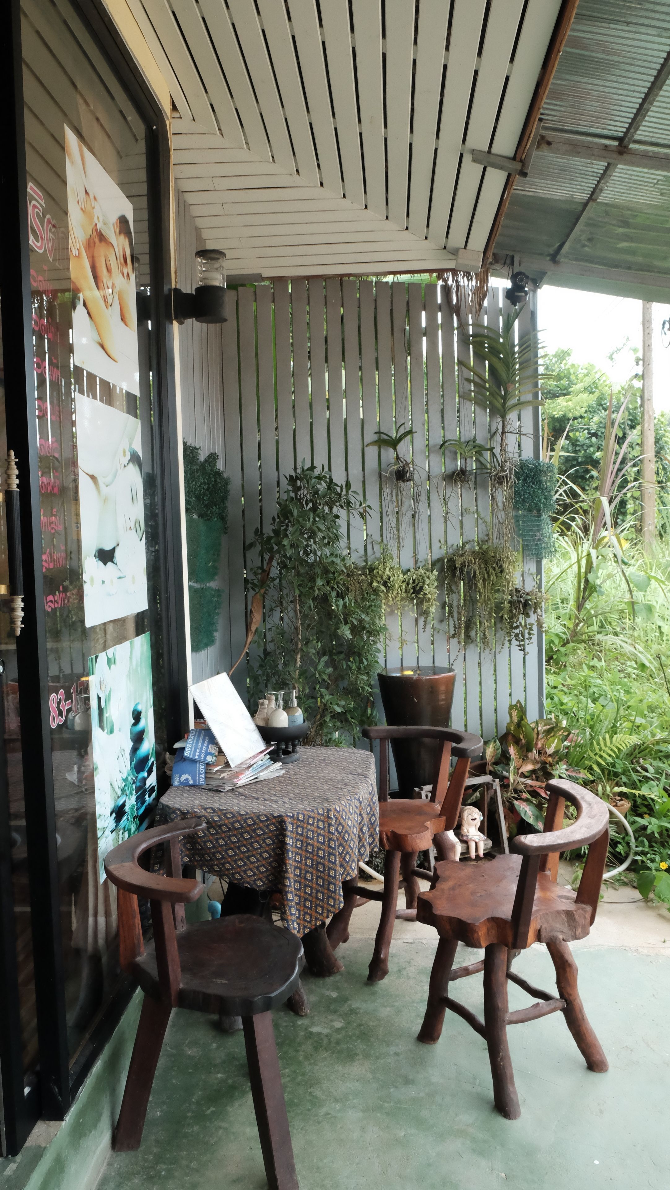 A covered outdoor seating area with wooden furniture and potted plants.