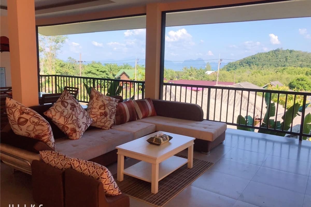 A modern living room with a sofa, coffee table, and a balcony with a scenic view.