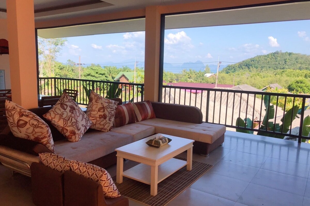 A modern living room with a sofa, coffee table, and a balcony with a scenic view.