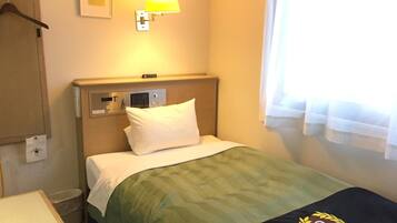 A hotel room with a bed, a control panel, a bedside lamp, a window with curtains, and a wall-mounted picture.