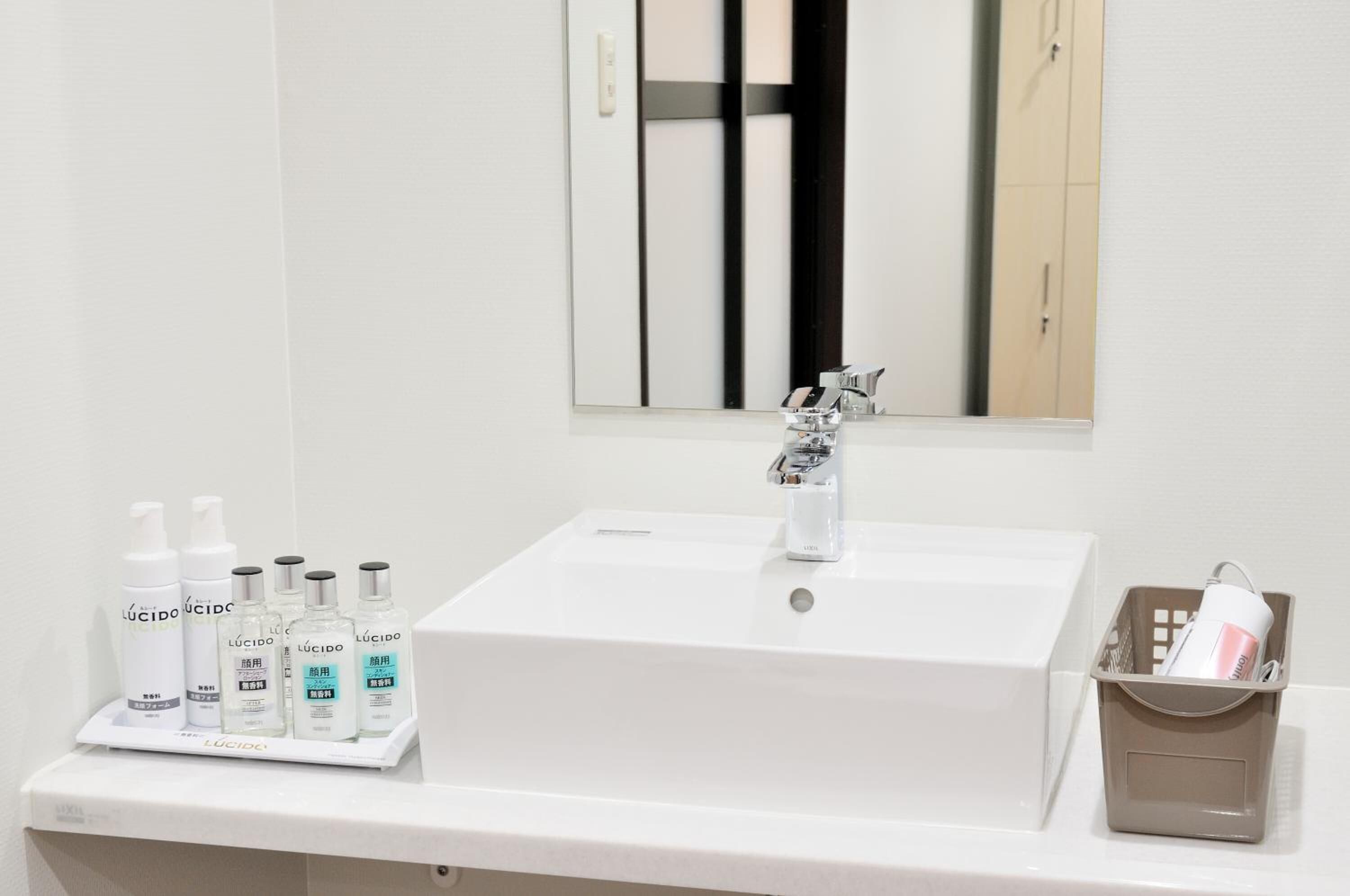 A bathroom with a white sink, a mirror, and a shelf with toiletries.