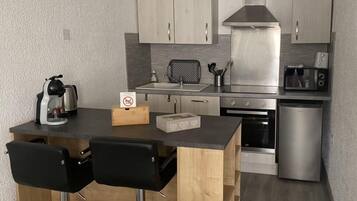 A compact kitchen with a central island, a microwave, a toaster, and a refrigerator.