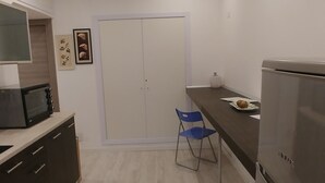 A modern kitchen with a microwave, refrigerator, and a blue chair. - Easy Holiday (Rome)