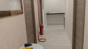 A hallway with a white round table, a fire extinguisher, and closed doors. - Easy Holiday (Rome)