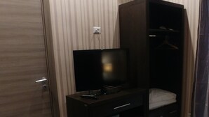 A bedroom with a bed, a TV on a stand, a wardrobe, and an air conditioning unit. - Easy Holiday (Rome)