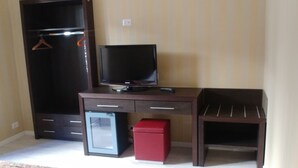 A room with a dark wooden desk, a small red storage box, a television, and a wardrobe with a hanging rack. - Easy Holiday (Rome)