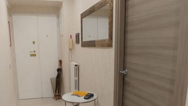 A hallway with a round table, a mirror, and a door. - Easy Holiday (Rome)